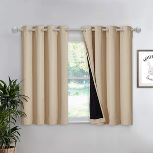 Beige blackout grommet top tier curtains covering a window, one panel showing black lining.