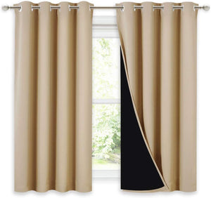 Beige blackout curtains with silver grommet tops, revealing dark lining on one pulled-back panel against a window.