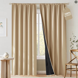 Pair of beige solid blackout curtains with a dark thermal lining, hanging on a decorative rod.