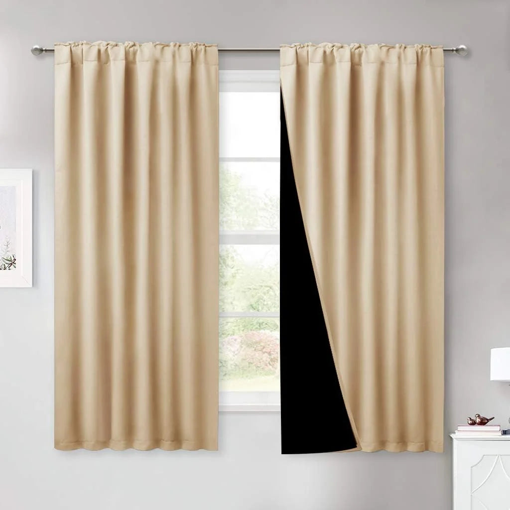 Beige blackout curtains on a silver rod with one panel pulled back to show black lining