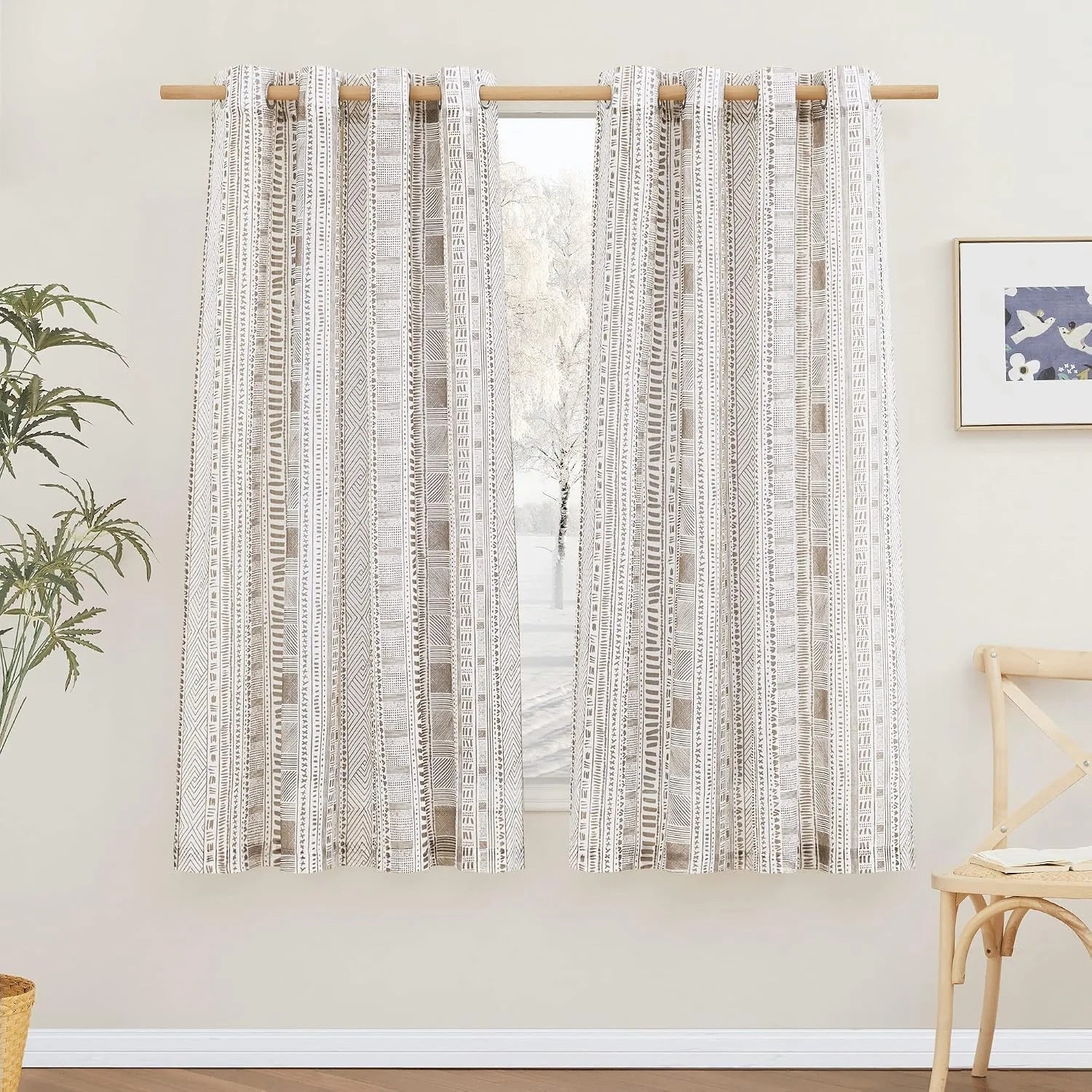 Beige and white boho geometric curtains on a wooden rod in a bright room