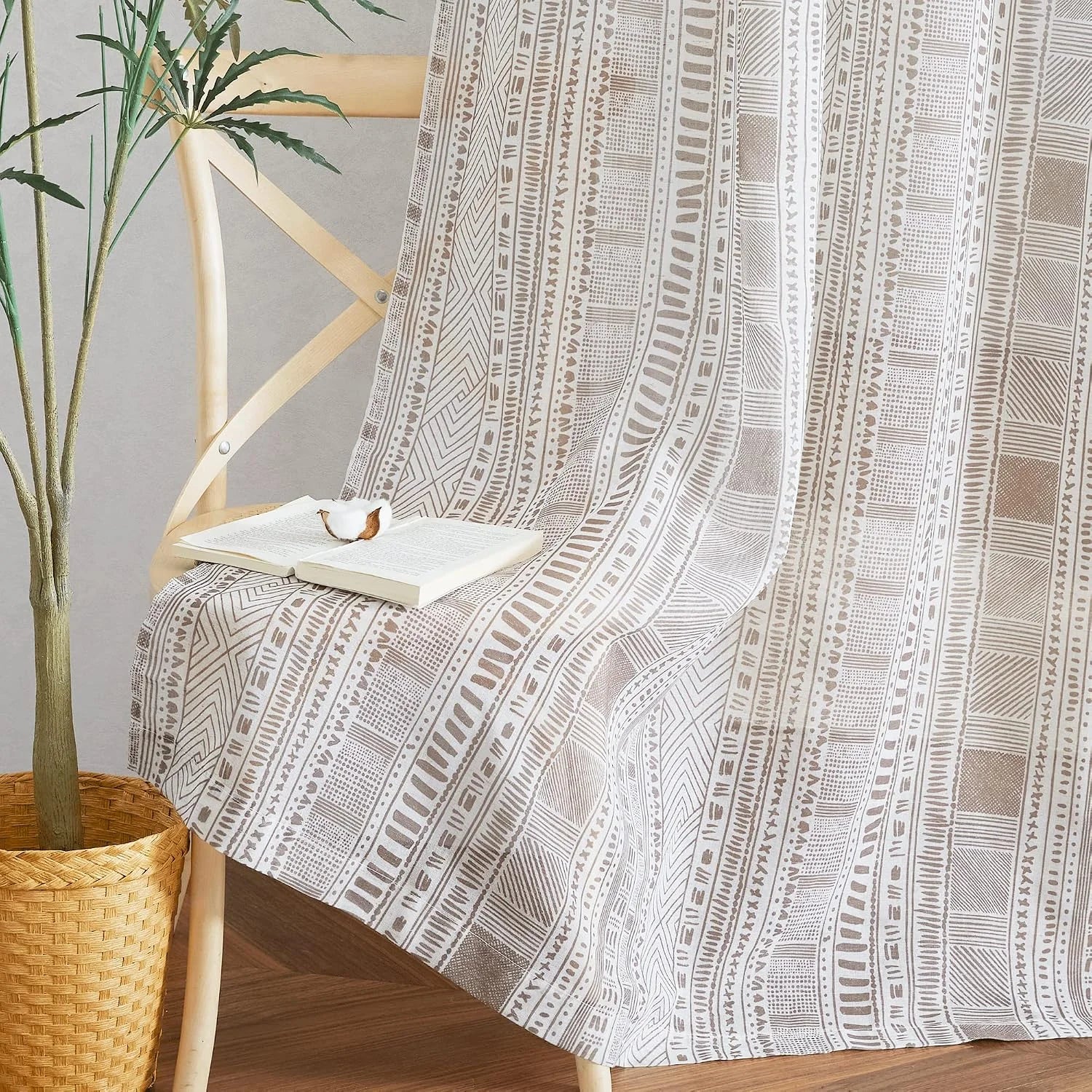 Beige boho geometric throw blanket draped over a wooden chair with an open book