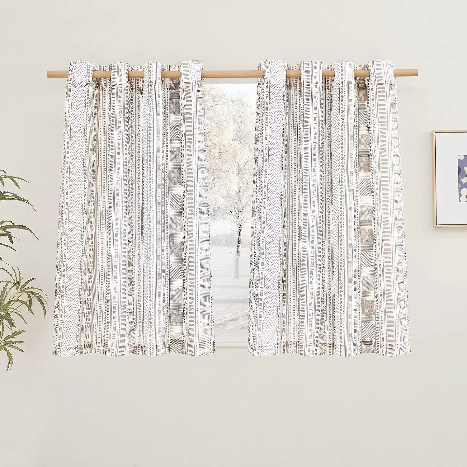 Beige and white boho geometric curtains on a wooden rod over a bright window