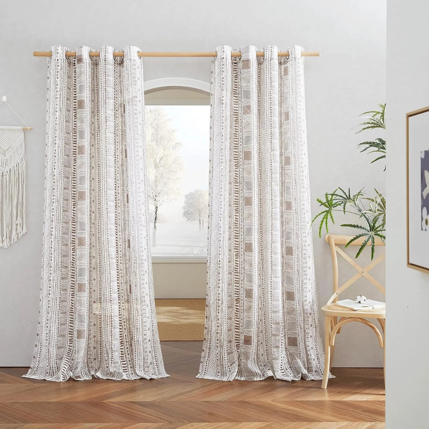 Beige boho patterned curtains on a wooden rod in a bright neutral room
