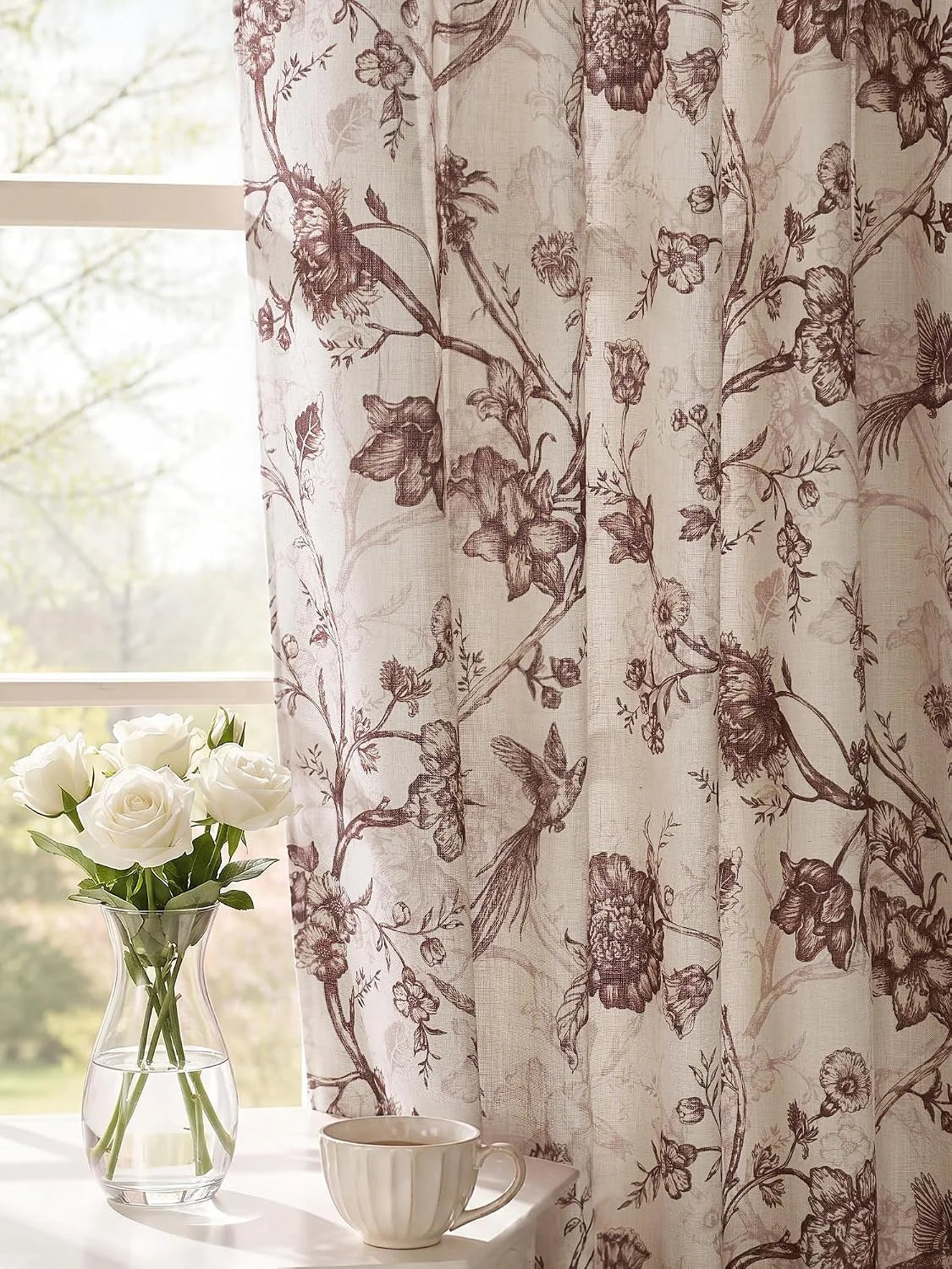 Beige linen-look curtain with brown floral and bird print beside a bright window