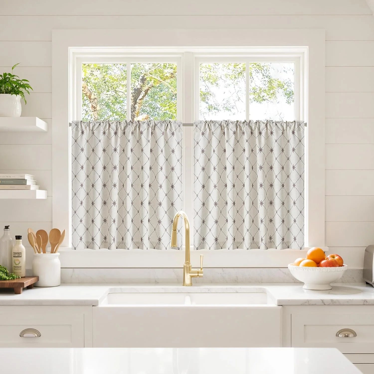Beige embroidered cafe curtains on a bright kitchen window above a farmhouse sink