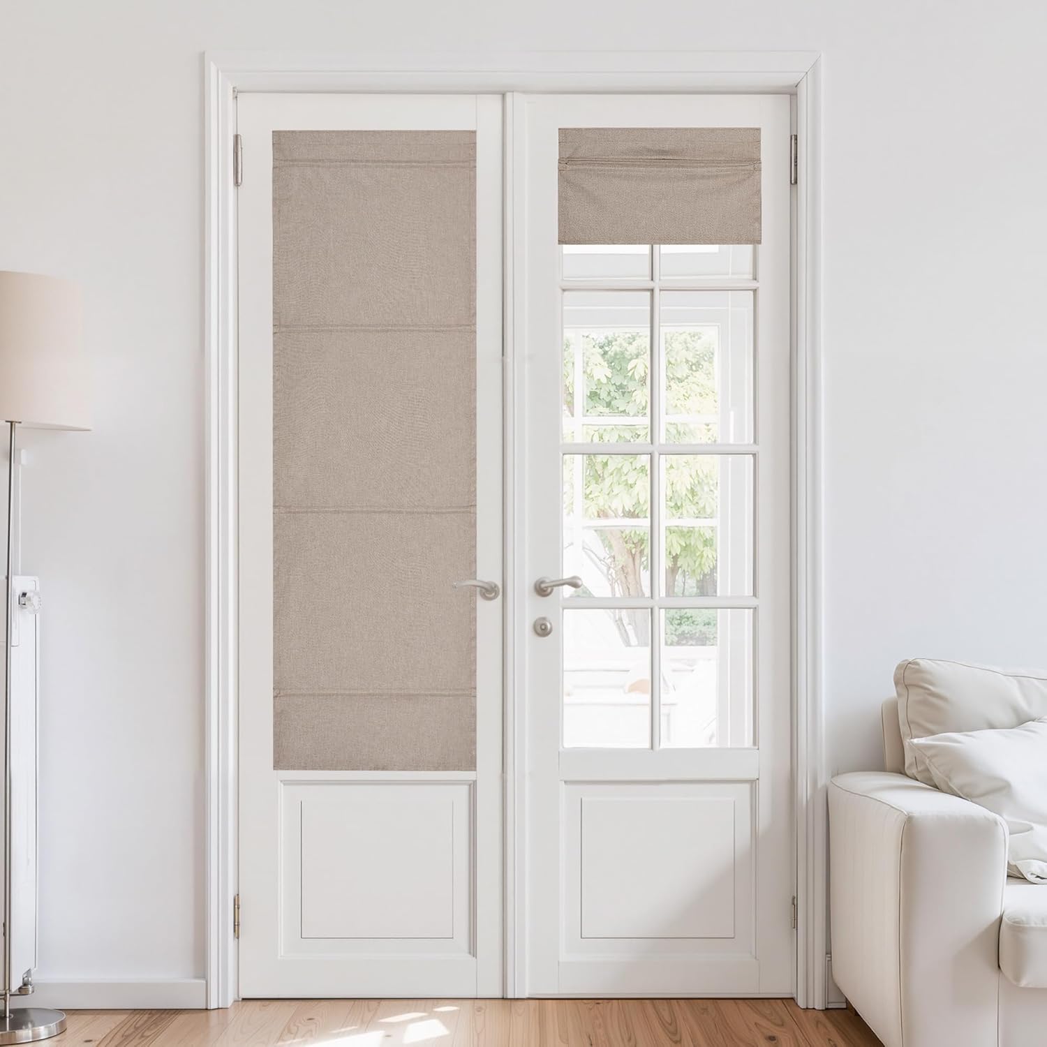 Beige flat fold roman shades installed on white French doors, one fully extended, the other partially raised in a bright room.