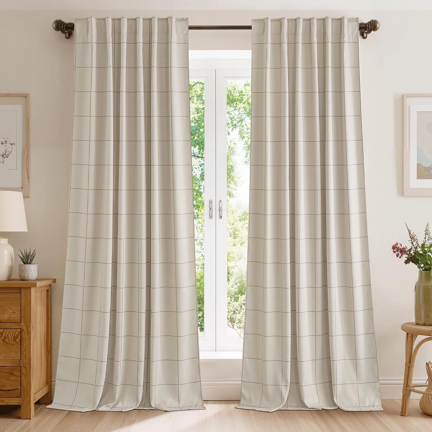 Pair of light beige grid pattern curtains hanging on a dark rod over a window, with natural light.