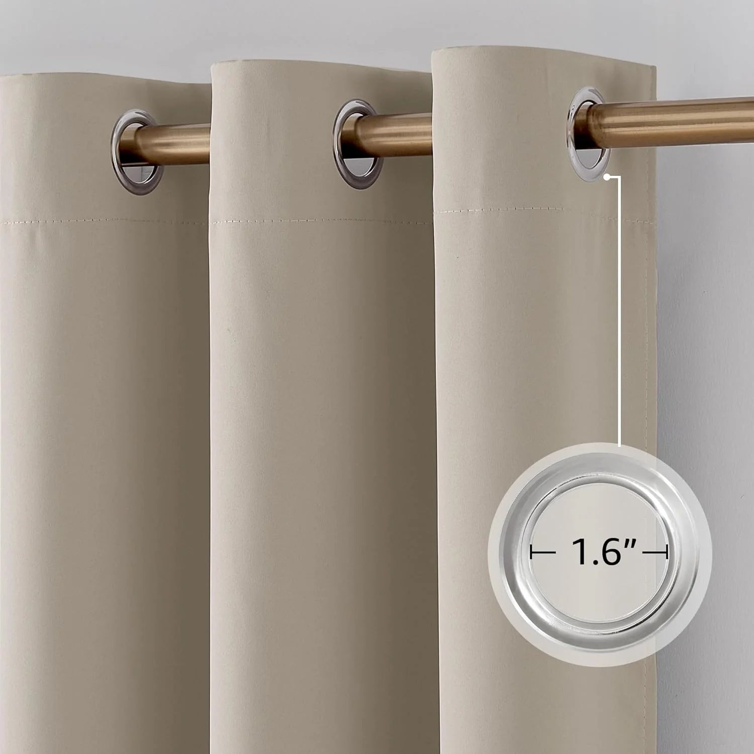 Close-up of beige blackout curtain with 1.6-inch silver grommets on a brass rod