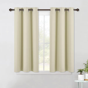 Pair of light beige blackout curtains with silver grommets hanging on a dark rod over a window.