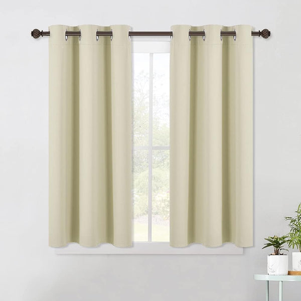 Pair of light beige blackout curtains with silver grommets hanging on a dark rod over a window.