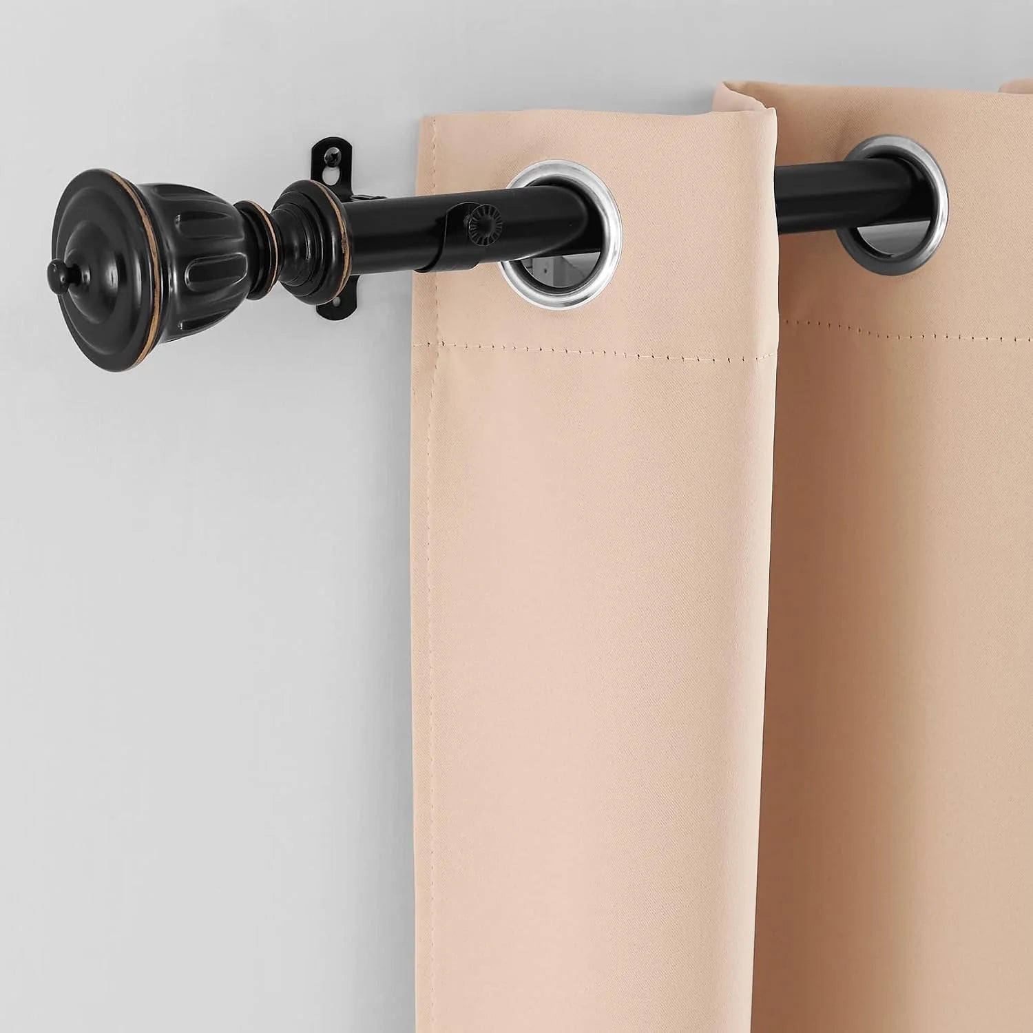 Beige grommet curtain panel hanging on a black decorative curtain rod