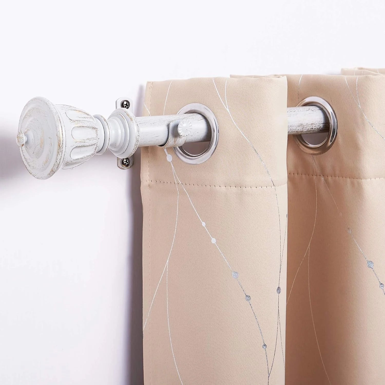 Beige grommet curtain panel on a distressed white rod with subtle stitched pattern