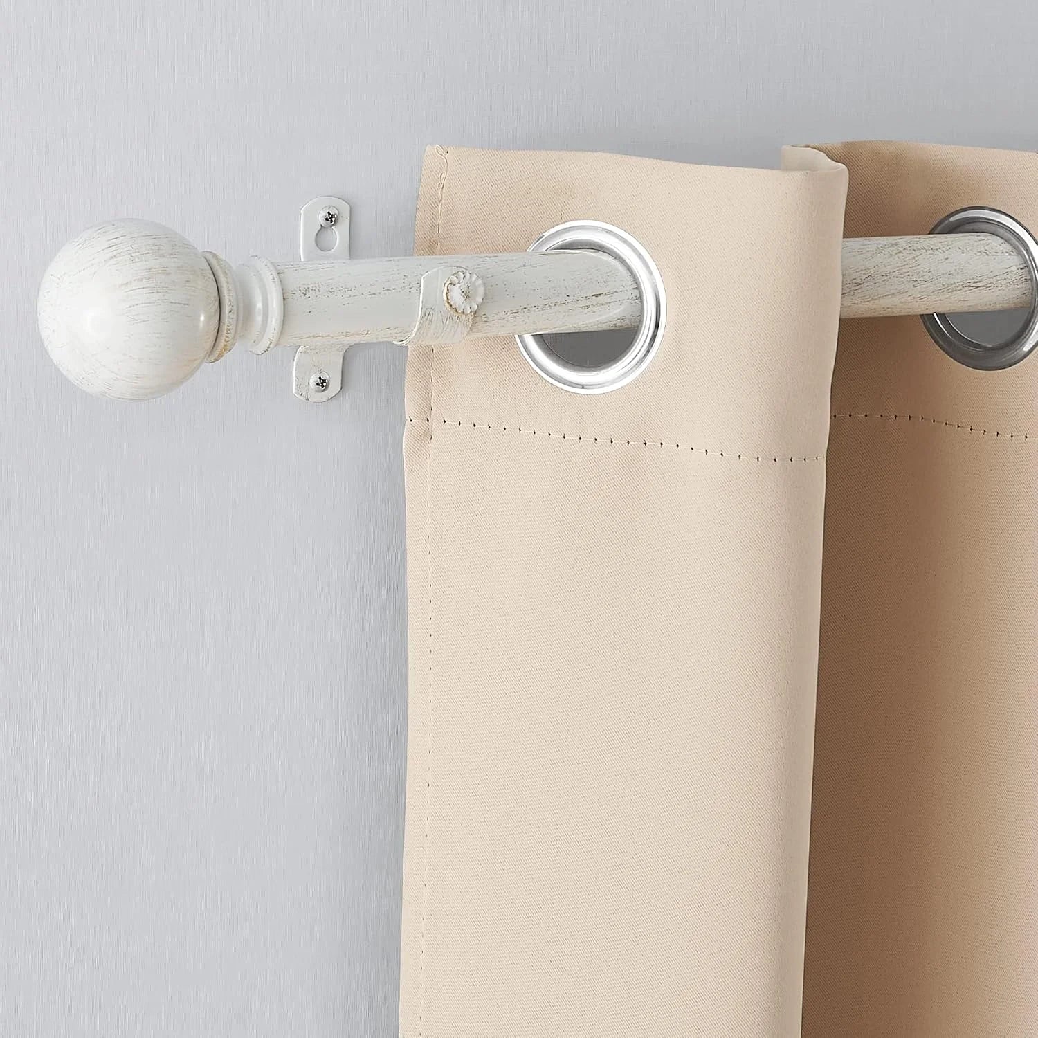Beige grommet curtain panel on a distressed white wooden curtain rod