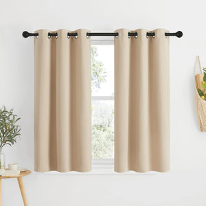 Light beige solid grommet top curtains hanging on a black rod over a window with outdoor view.