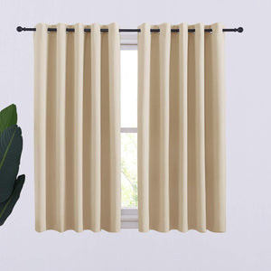 Pair of light beige blackout curtains with grommet tops on a black rod over a window.