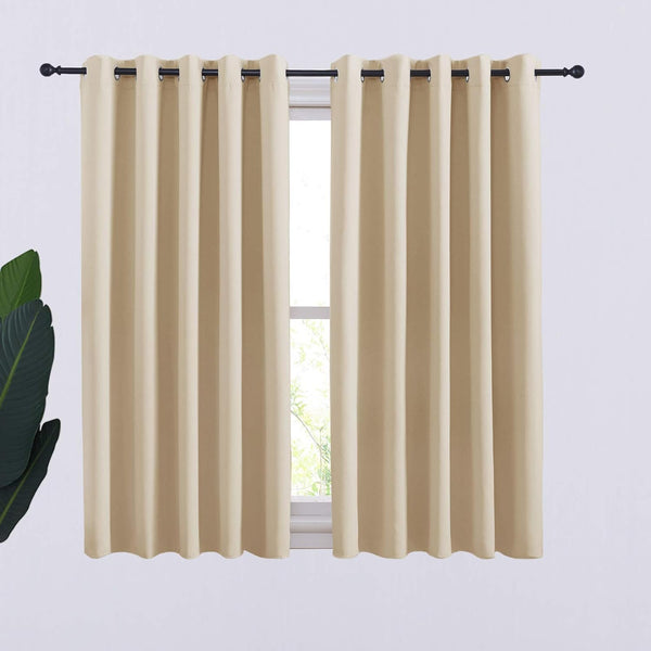 Pair of light beige blackout curtains with grommet tops on a black rod over a window.