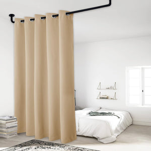 Beige grommet top room divider curtain hanging from a ceiling-mounted black rod in a bedroom.