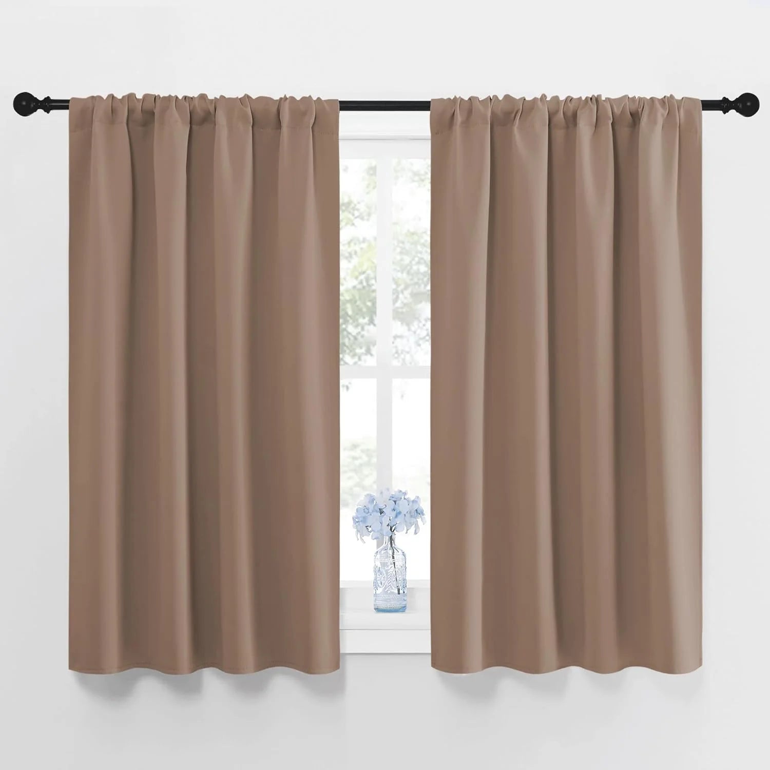 Taupe rod pocket cafe curtains covering a window, with a vase of blue flowers on the sill.