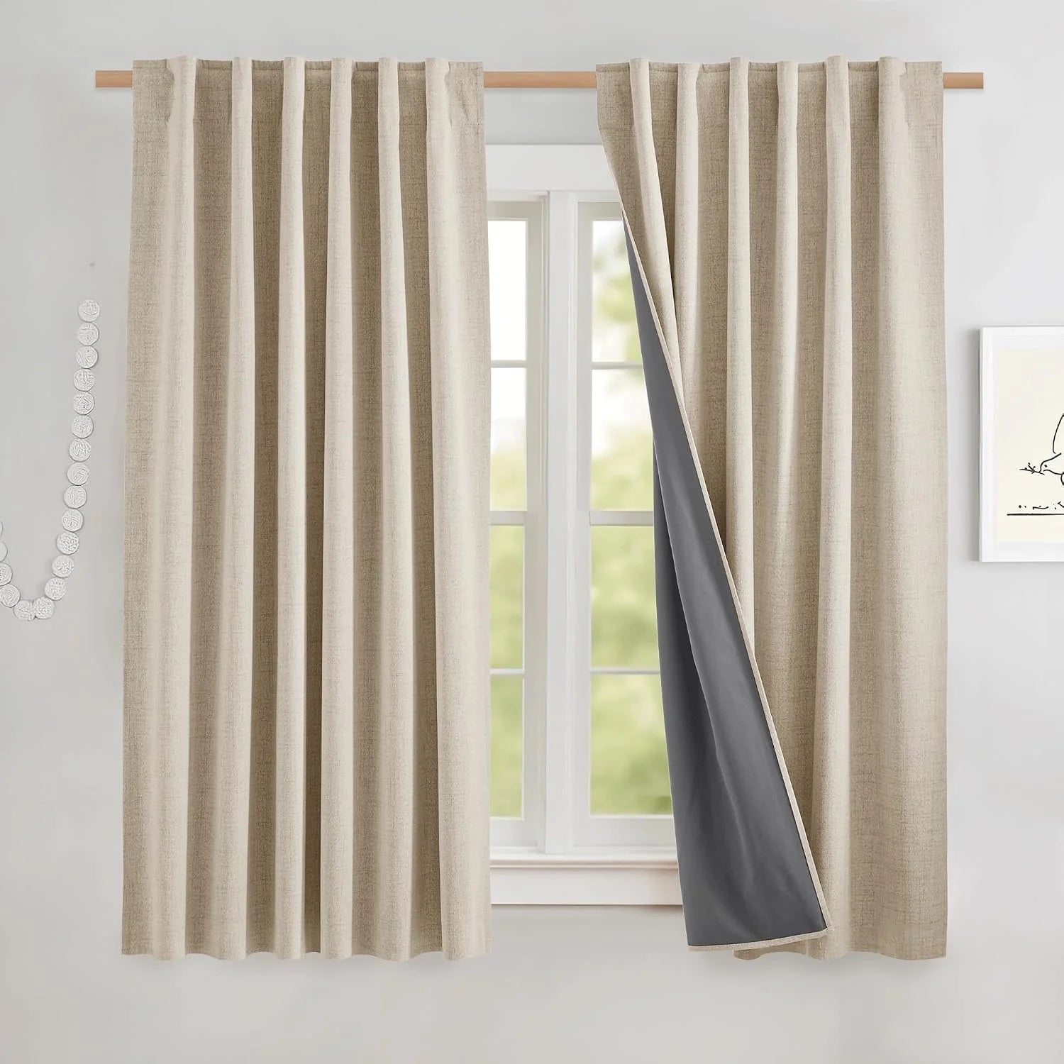 Beige linen-look blackout curtains with pleated top on a wooden rod by a bright window
