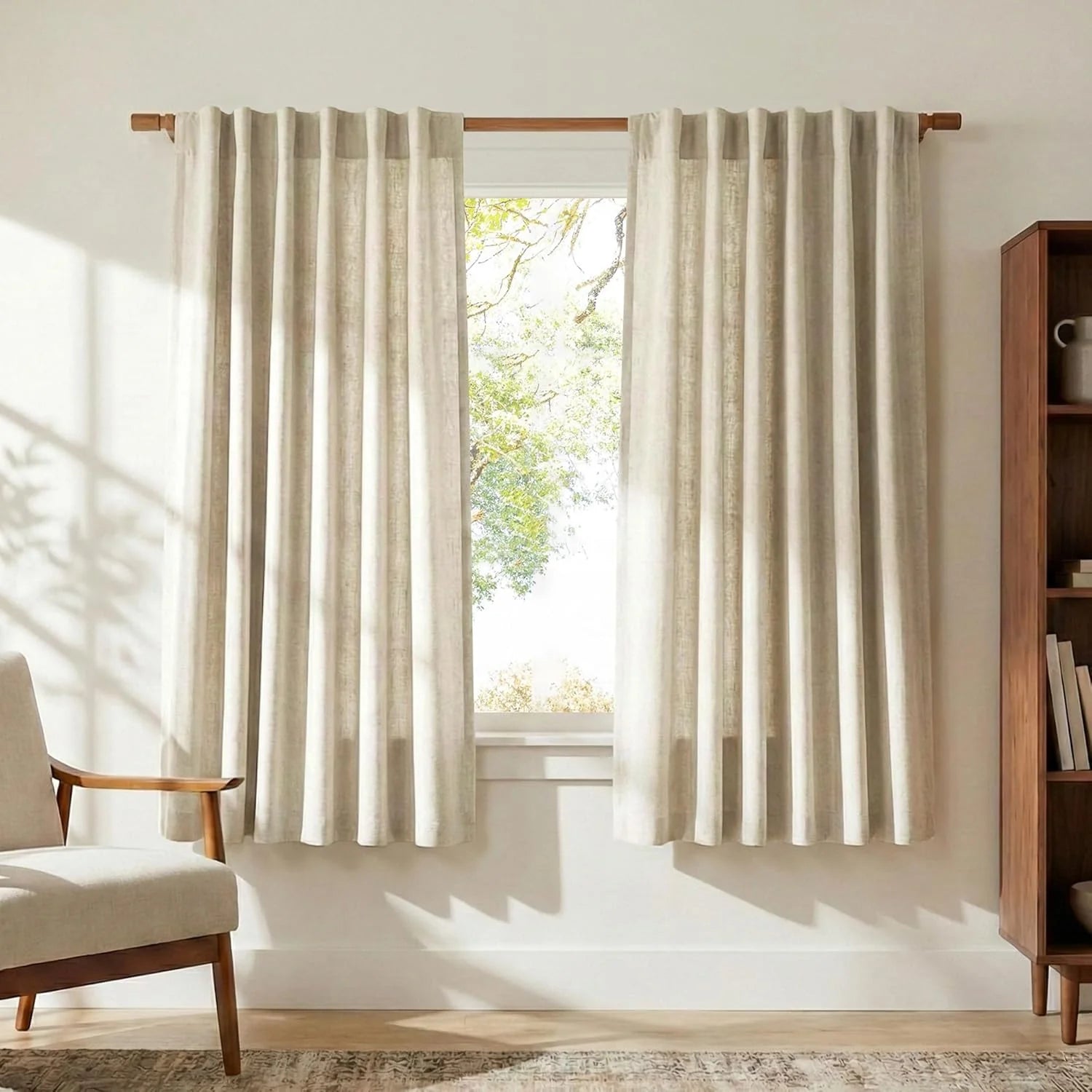 Pair of light beige linen curtains on wooden rod in modern living room.