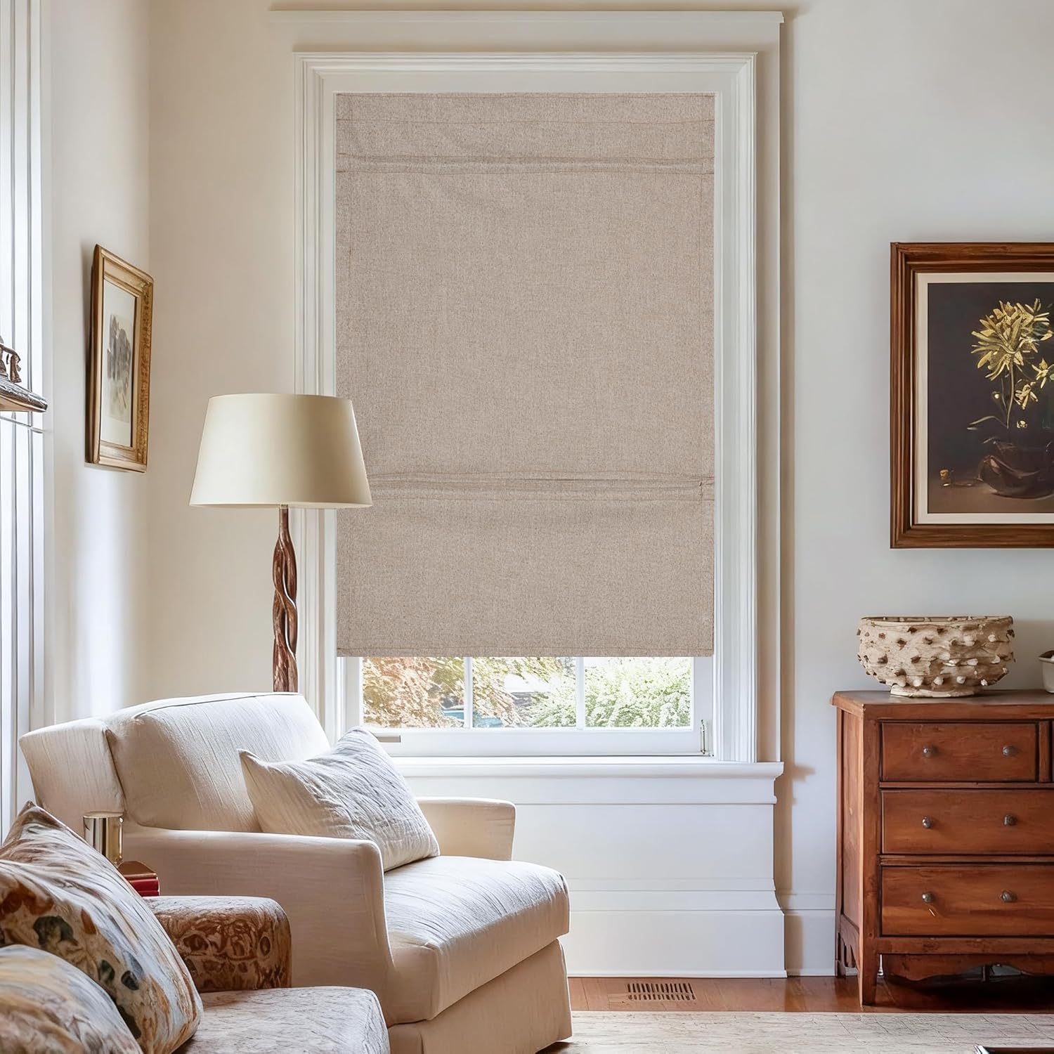 Tailored beige linen roman shade with crisp folds in a sunlit living room window.