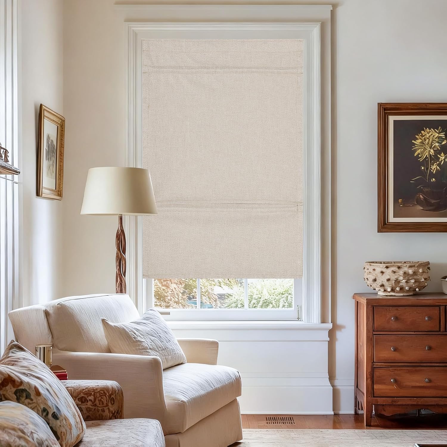 Light beige textured linen flat fold roman shade covering a window in a cozy living room.