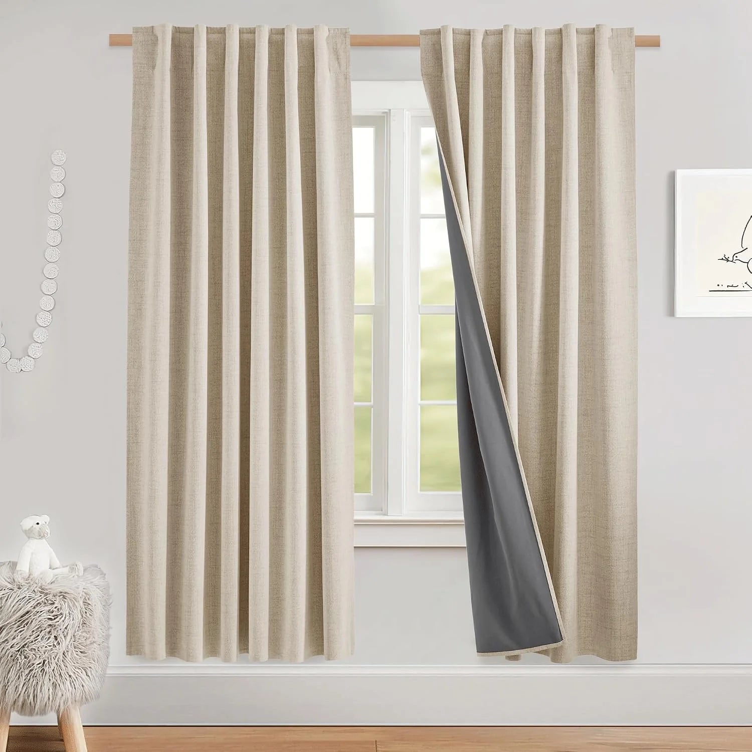 Beige linen-look blackout curtains with pencil pleats on a wooden rod by a bright window