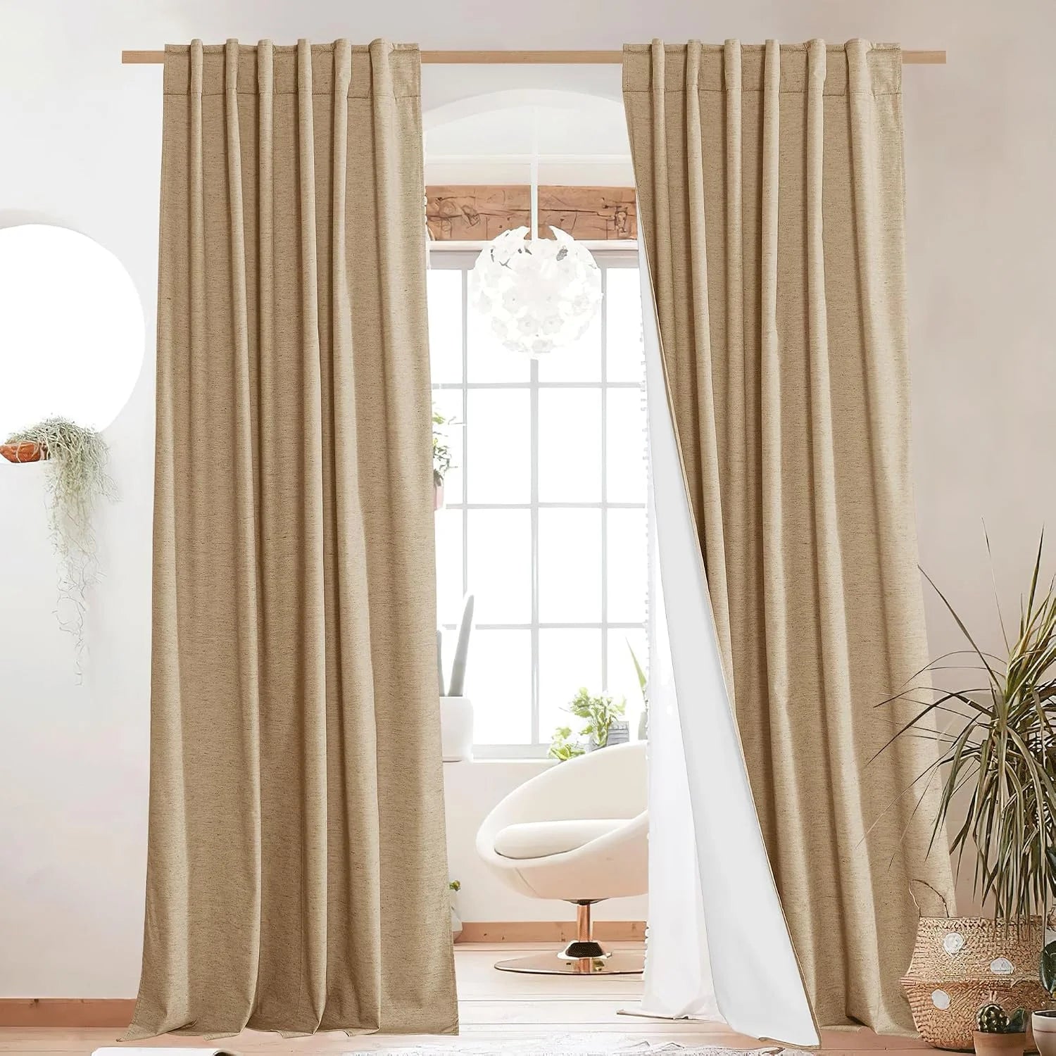 Beige linen-look pleated curtains hanging on a wood rod in a bright modern room
