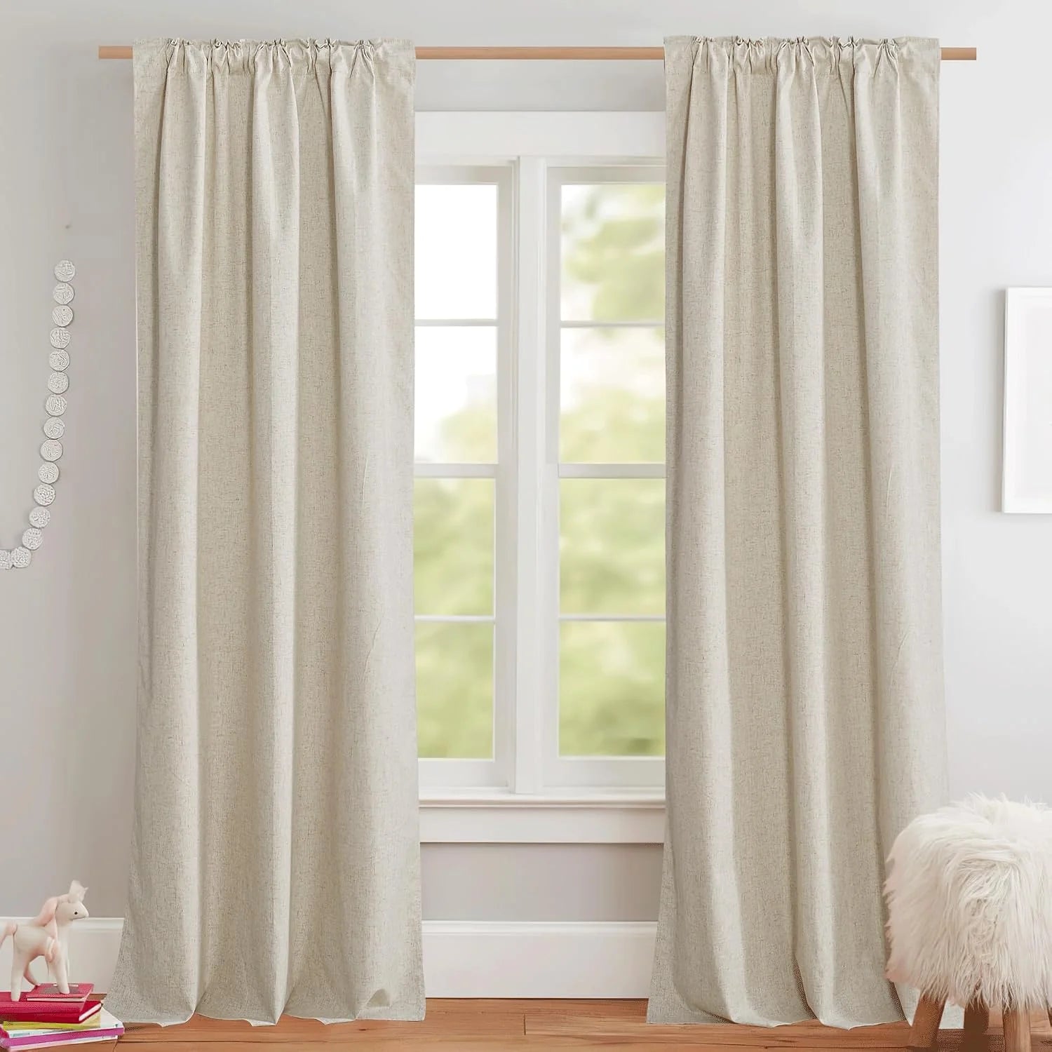 Beige linen-look rod pocket curtains hanging over a white framed window