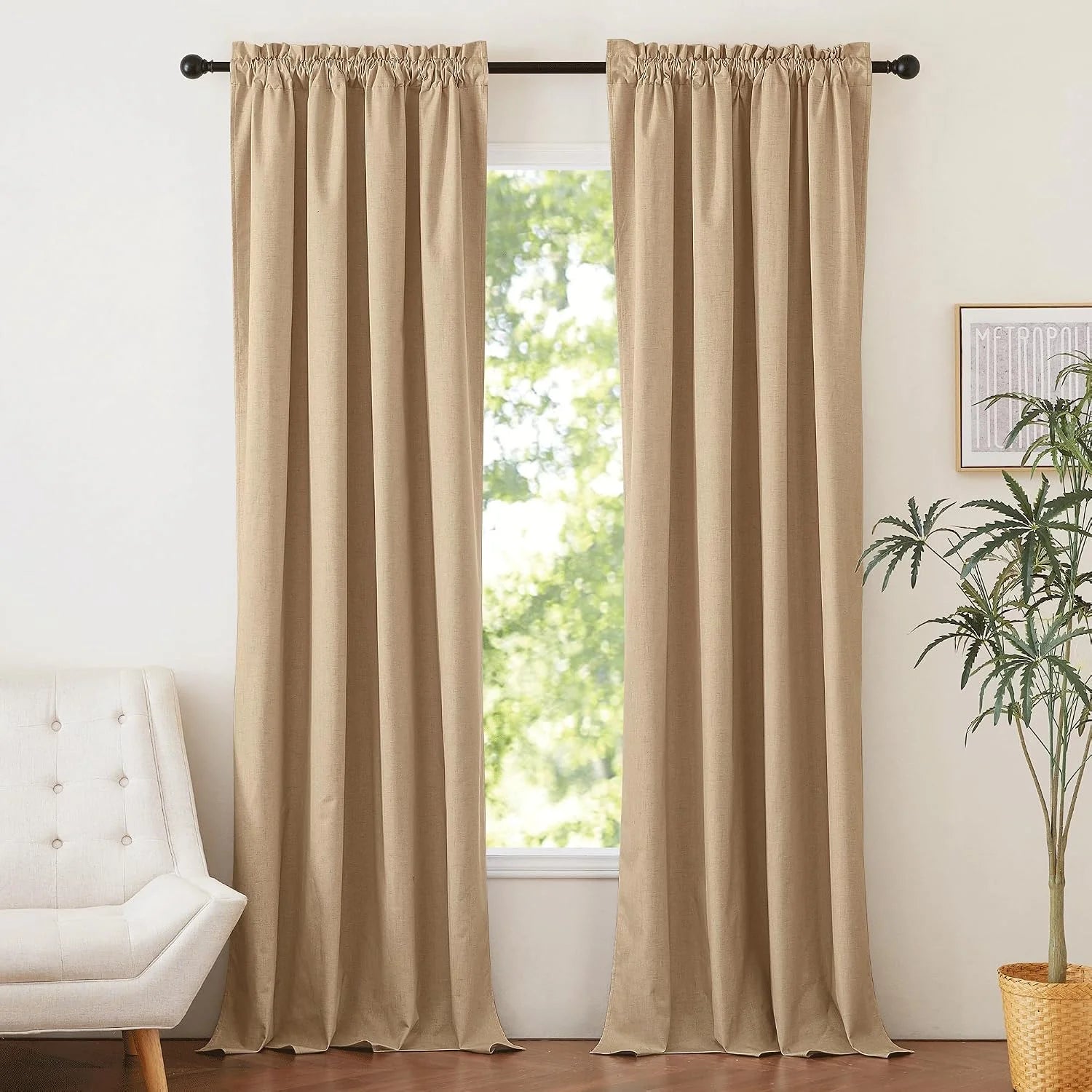 Beige linen-look rod pocket curtains hanging on a dark rod in a bright neutral room