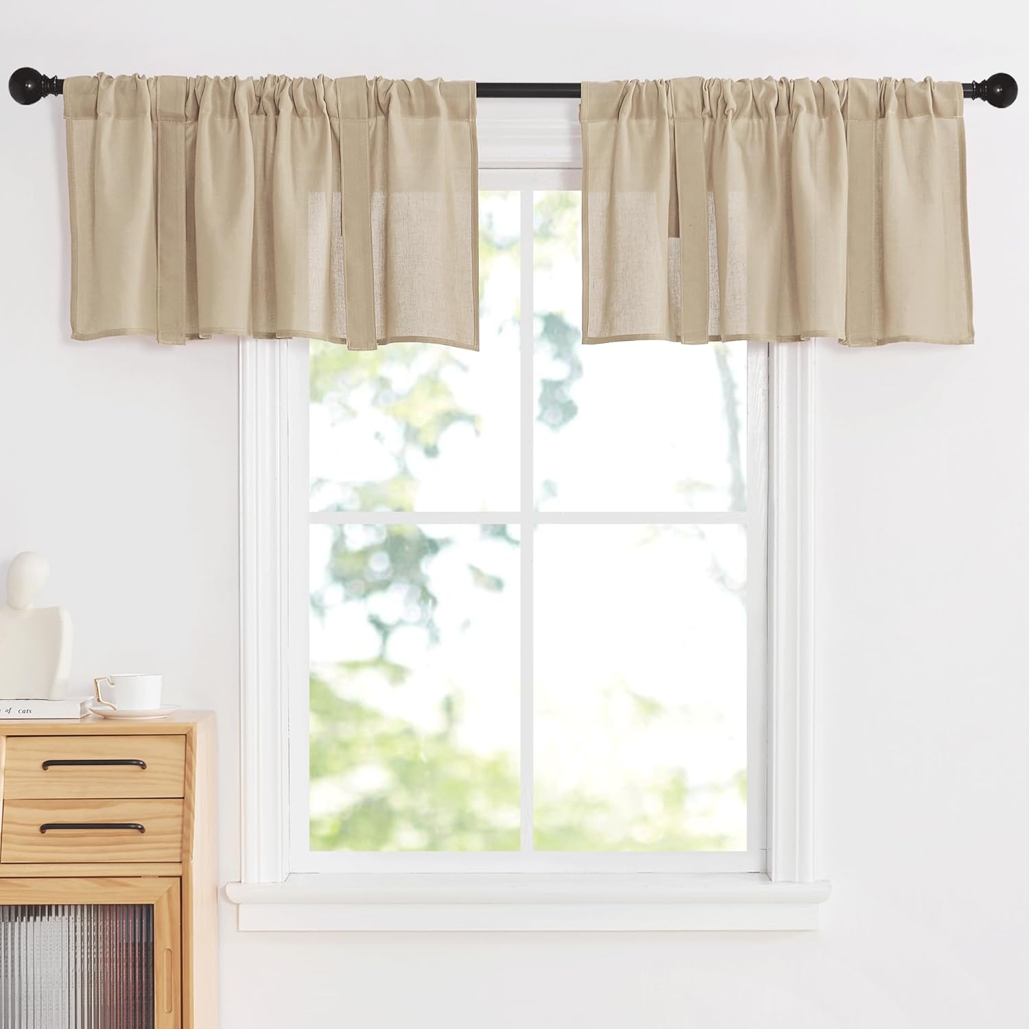 Beige linen look rod pocket window valance with gathered fabric hanging on a black curtain rod above a window.