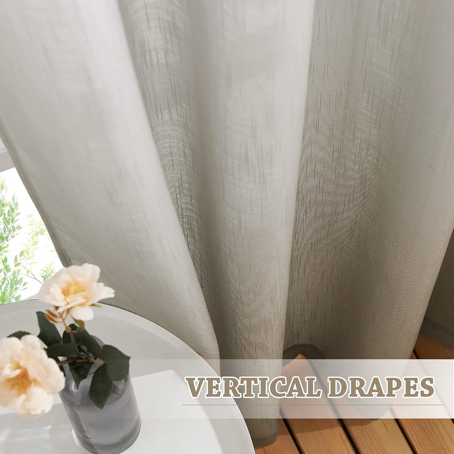 Beige linen-look sheer drapes with vertical folds beside a white table and flowers