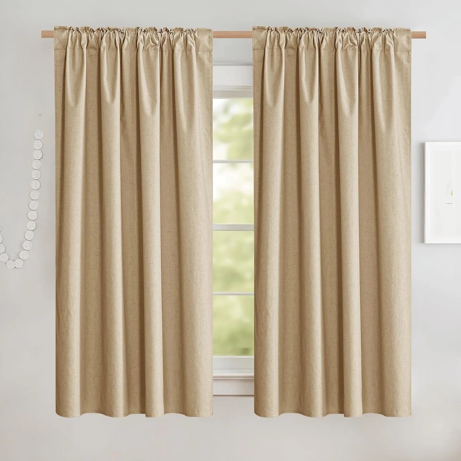 Beige linen-look rod pocket curtains hanging on a wooden pole over a bright window