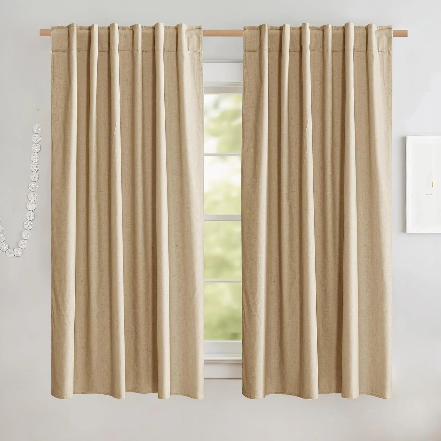 Beige linen-look rod pocket curtains hanging on a wooden rod in a bright room