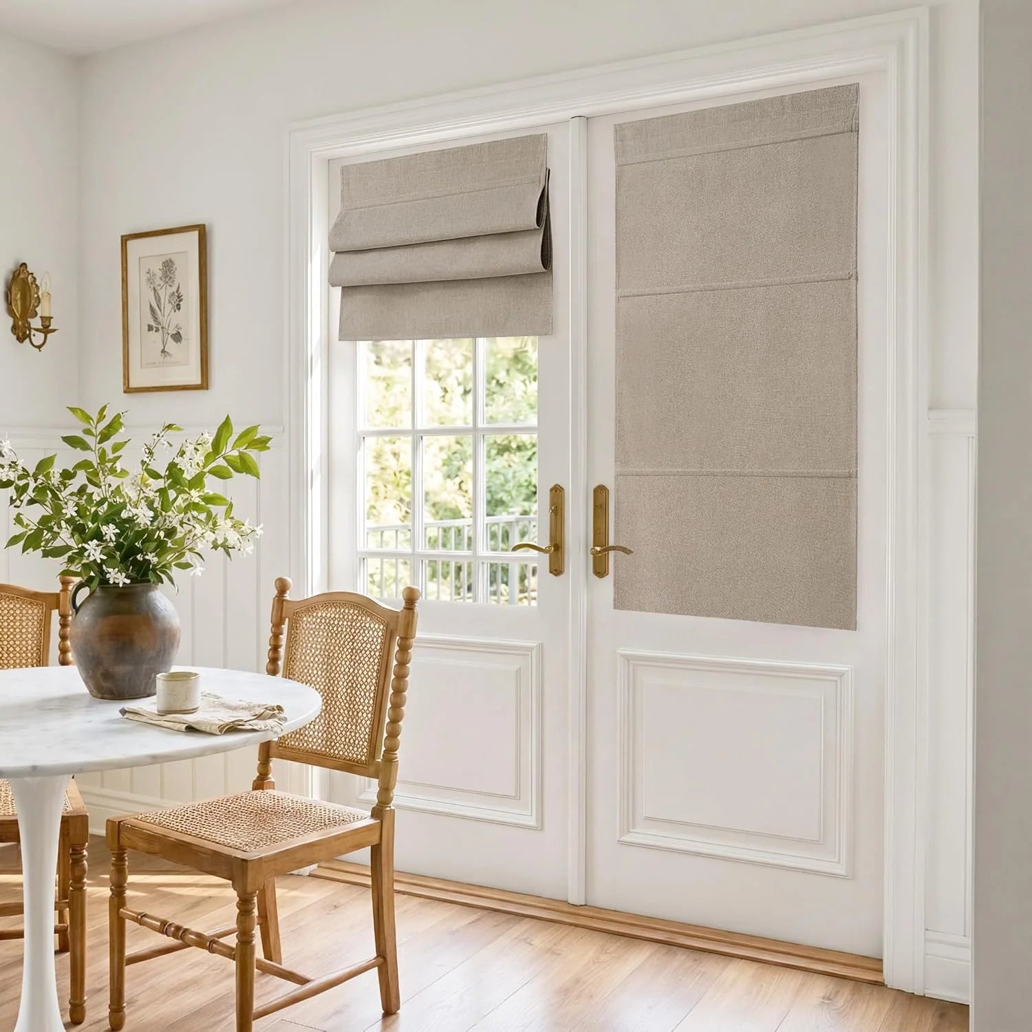 Light beige linen roman shades on white French doors in a bright dining area with marble table.