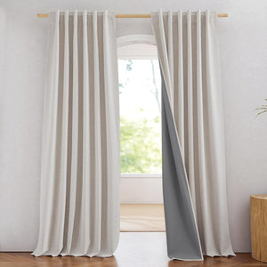Light beige textured linen curtains with visible dark grey blackout lining hanging on a wooden rod.