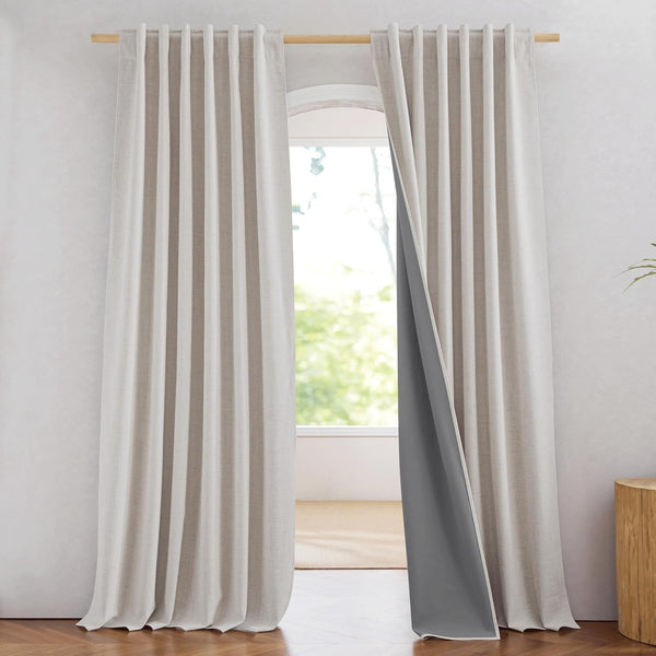 Light beige textured linen curtains with visible dark grey blackout lining hanging on a wooden rod.