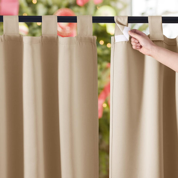 Close-up of beige outdoor curtains with a hand demonstrating the hook-and-loop tab top closure on a black rod.