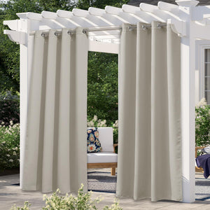 Beige outdoor patio curtains with silver grommet tops hanging from a white wooden pergola.