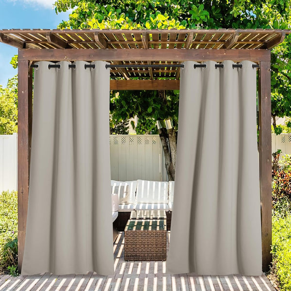 Beige outdoor curtains with black grommet tops hanging from a wooden pergola, enclosing a patio seating area.