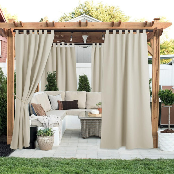 Beige tab top outdoor curtains hang from a wooden pergola, offering patio privacy. One panel tied back.