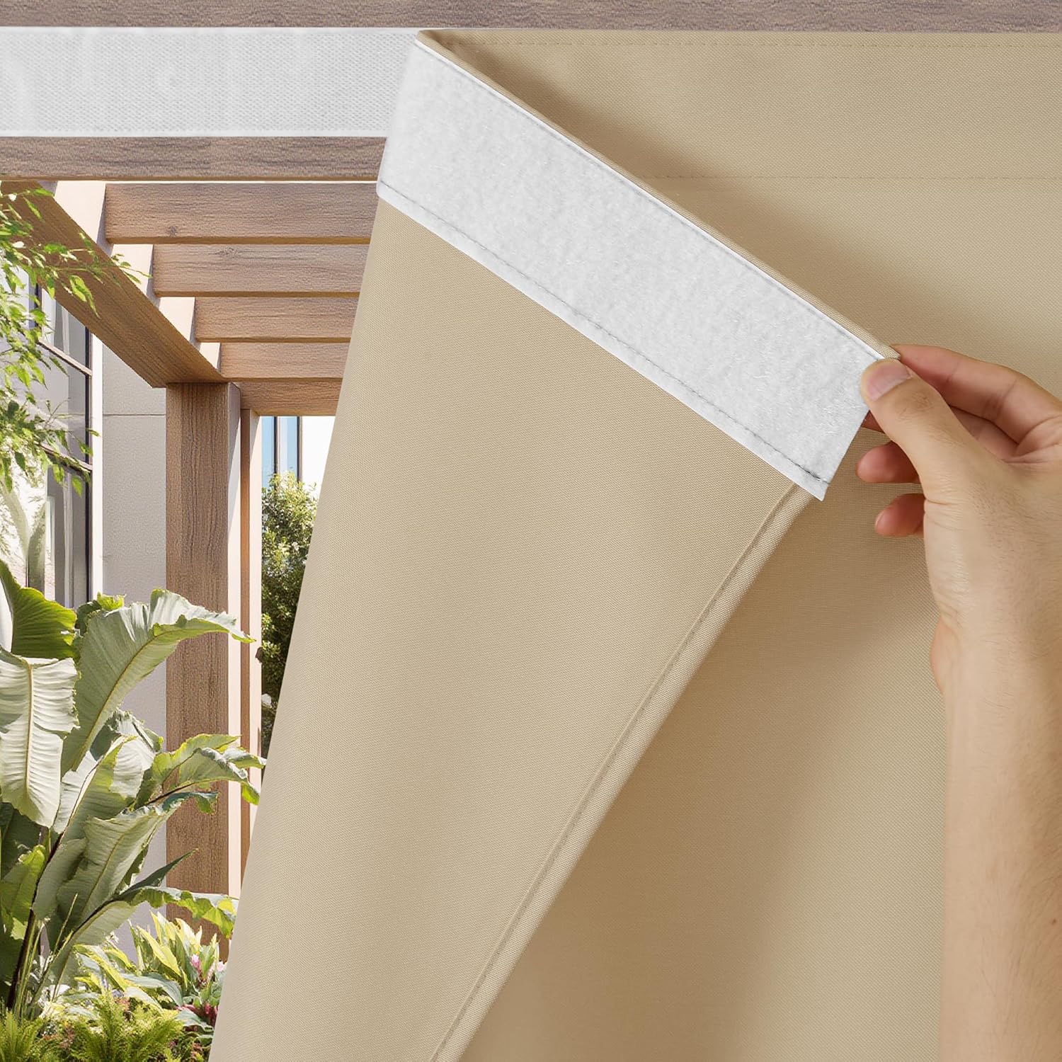 Hand attaches beige outdoor shade with white velcro. Wooden pergola and green plants visible.