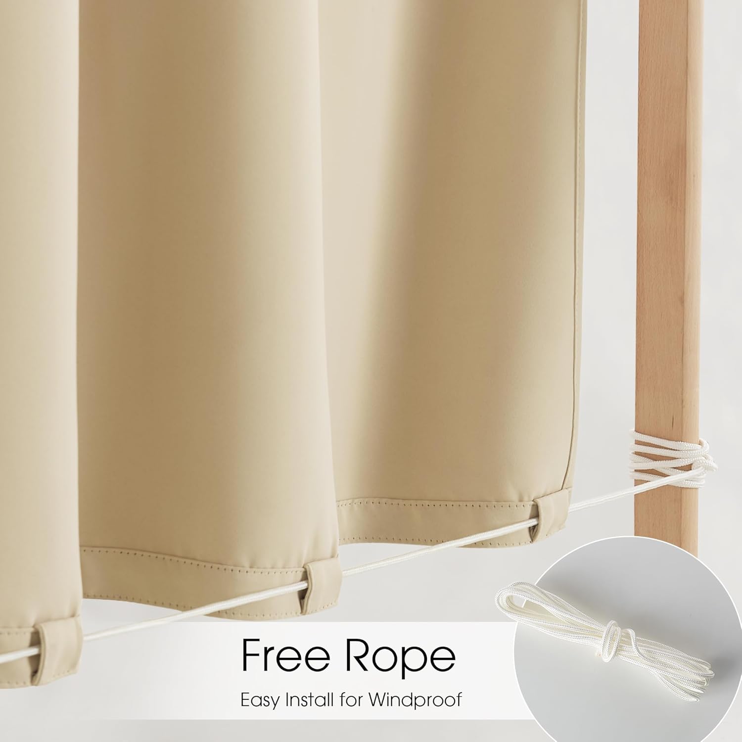 Windproof beige outdoor curtain secured by white rope to wooden post. A coil of rope is visible.