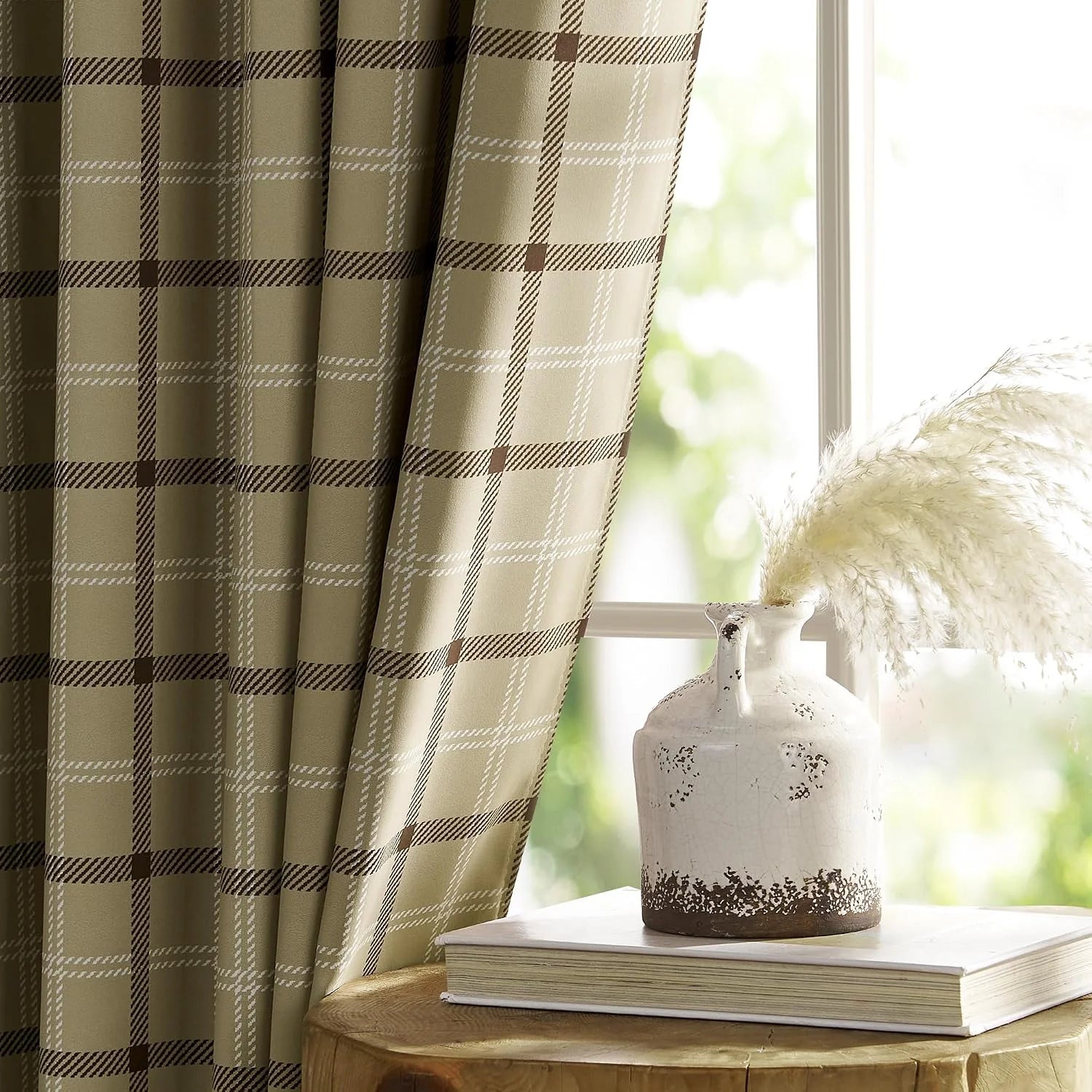 Beige plaid curtain panel beside a bright window with a rustic ceramic vase