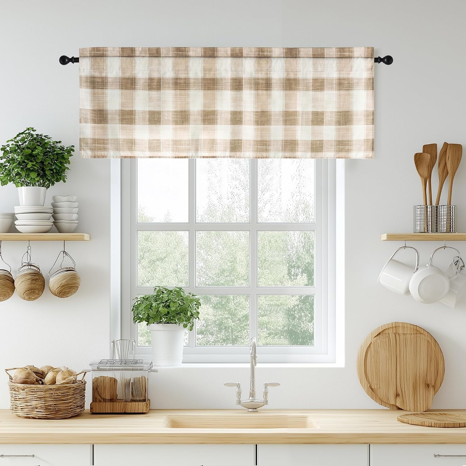 Beige and white plaid farmhouse window valance hanging on a black rod over a kitchen sink with plants.