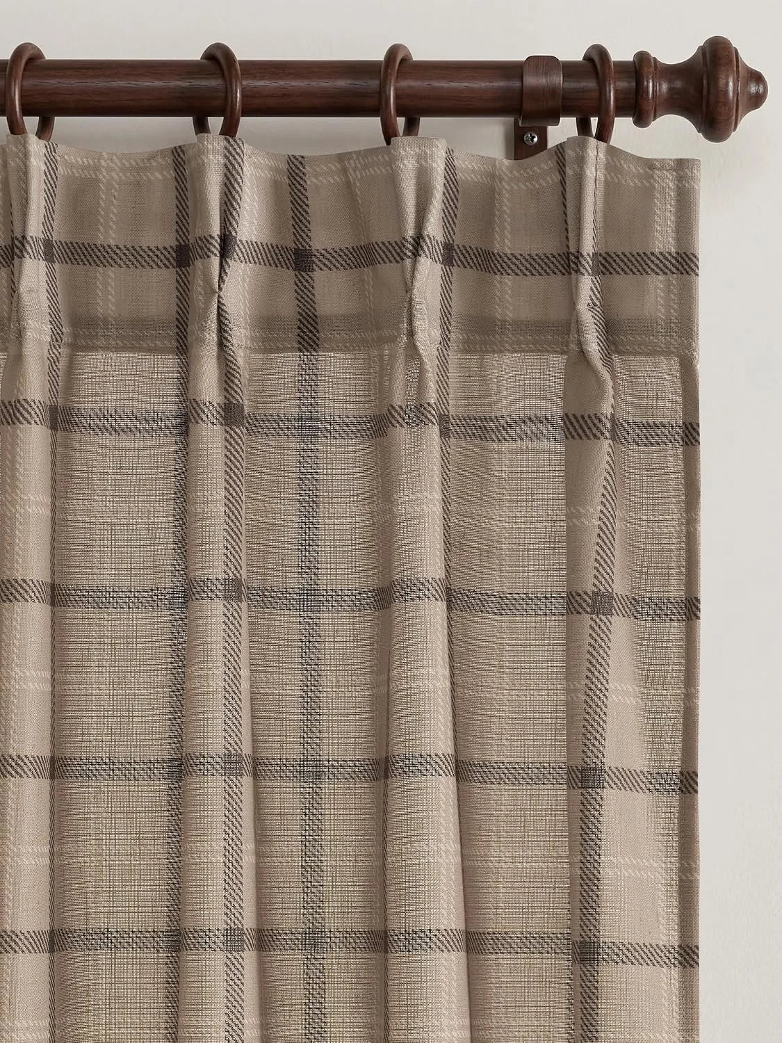 Beige plaid curtain panel with tab top hanging on a dark wooden rod