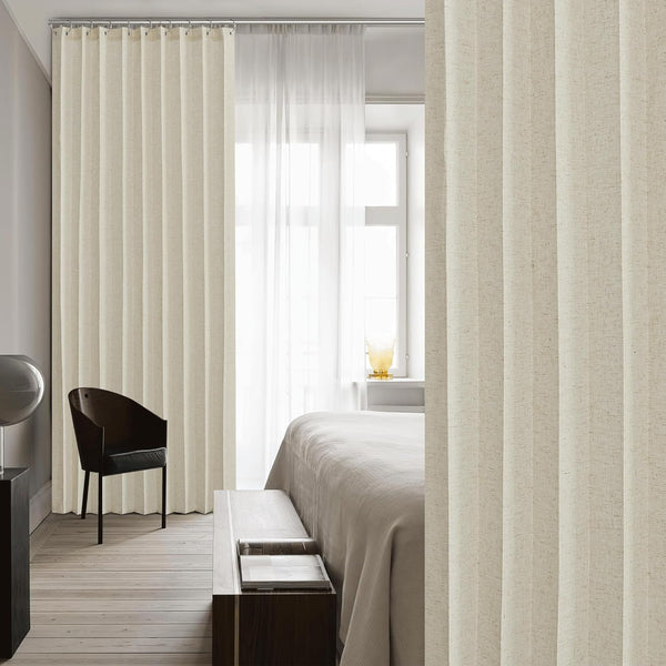 Textured beige linen pleated curtain panel on a silver rod, dividing a modern bedroom space.