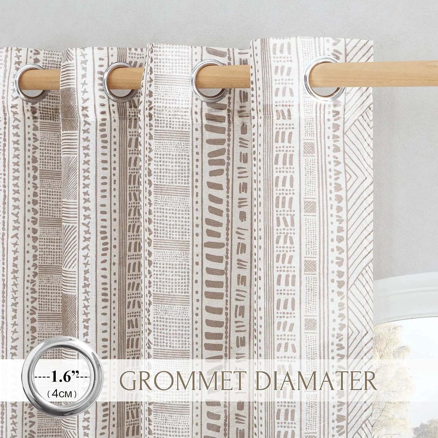 Beige patterned curtain panel with silver grommets on a light wood curtain rod