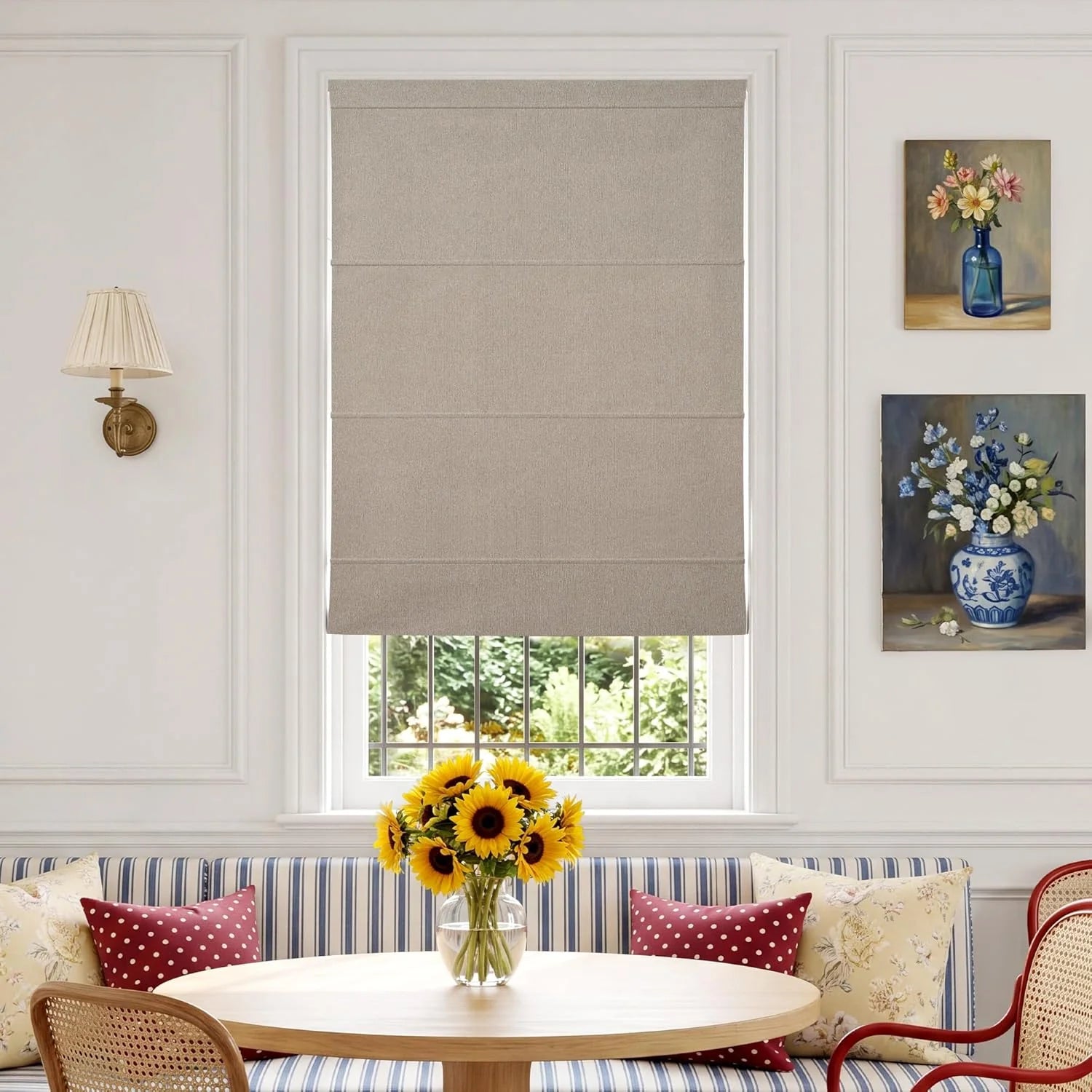 Beige textured Roman shade over window in cozy dining nook with striped bench and sunflowers.